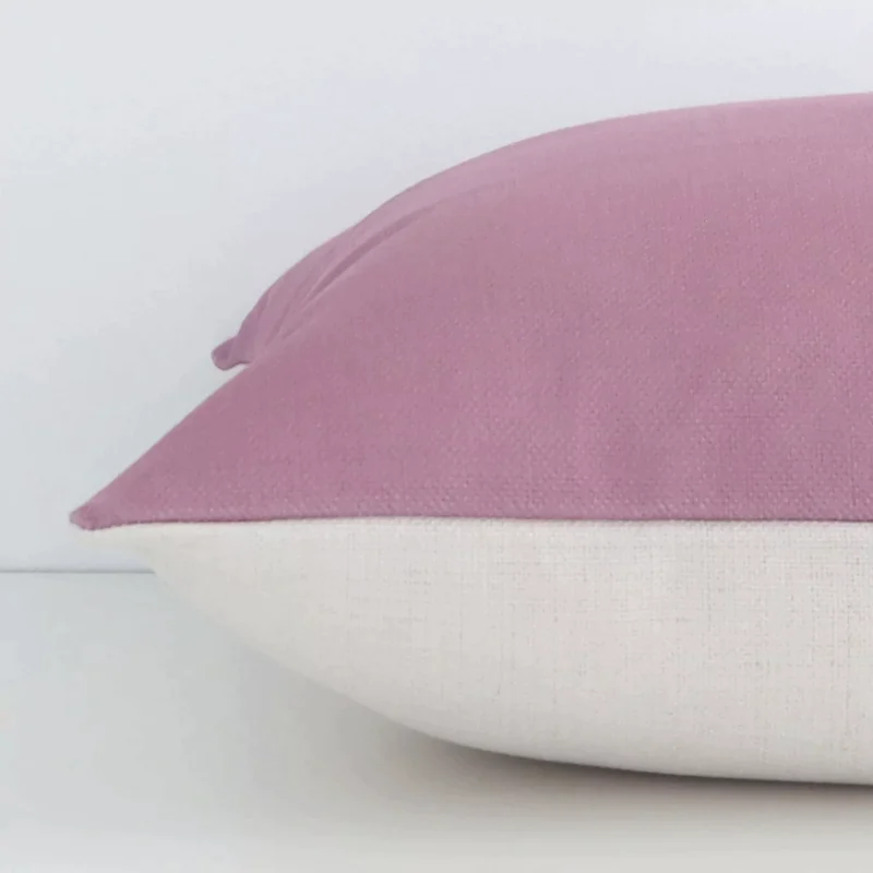 Horizontal edge of solid colour square cushion cover is shown. The linen fabric and blush tone can be seen from this side view.
