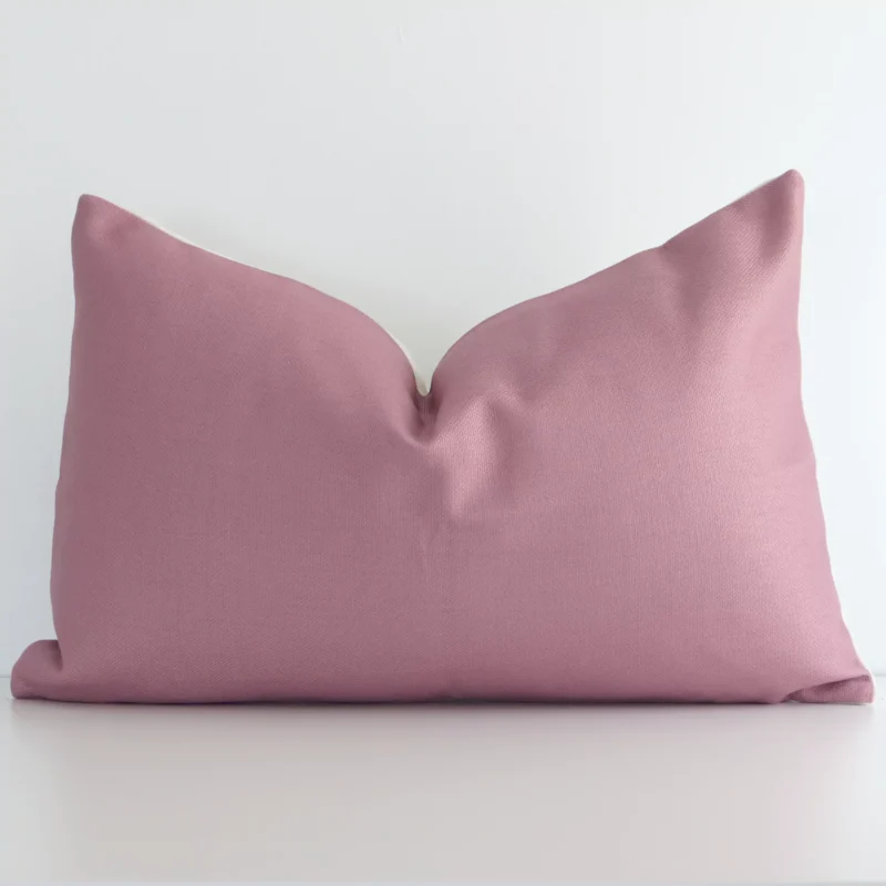 norse-blush-rectangular-cushion-cover---rectangle---sc656-30 Blush solid coloured cushion positioned in front of a white wall. It has rectangle shape and is made from a linen material.
