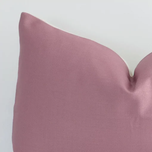 Extreme close up of a rectangle blush cushion. The solid colour style and linen fabric are shown with a much higher degree of detail.