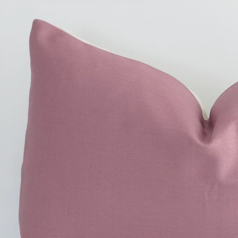 Extreme close up of a rectangle blush cushion. The solid colour style and linen fabric are shown with a much higher degree of detail.