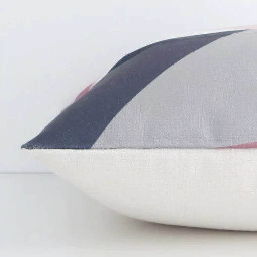 A colourful geometric cushion arranged sideways in front of a wall. The square shape and linen fabric are shown and the seams are clearly visible.