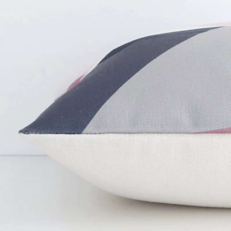 A colourful geometric cushion arranged sideways in front of a wall. The square shape and linen fabric are shown and the seams are clearly visible.