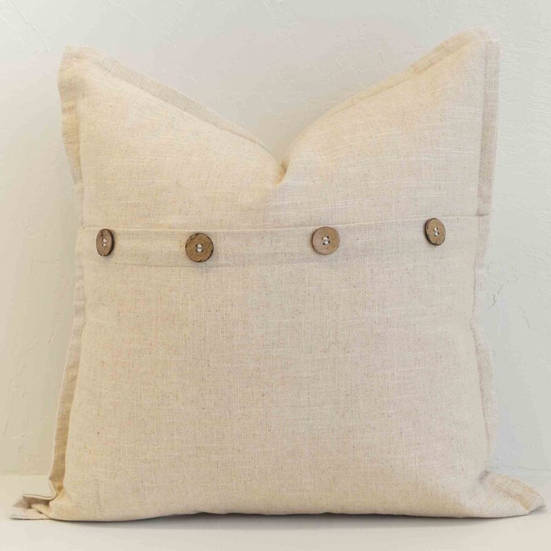 Oatmeal linen cushion with button closure detail and natural woven texture.