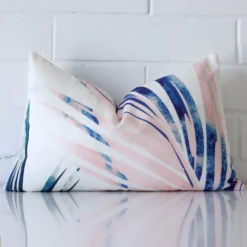 A rectangle cushion cover that has a unique design is shown vertically against a brick wall. It has a wonderful pink colour.