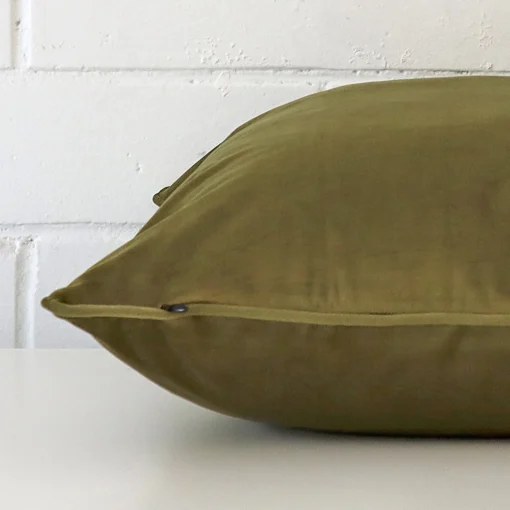 Side image of a velvet large cushion cover. The olive colour is more visible from the side showing the attachment of the panels.