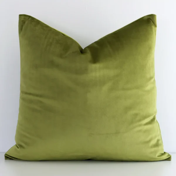 An attractive solid-coloured velvet cushion in front of a white wall. It has a rectangle shape and is olive in colour.