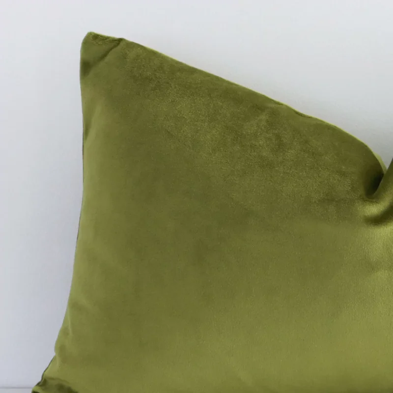Magnified view of this velvet olive cushion cover’s corner showing a solid coloured design and its rectangle shape.