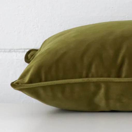 A side shot of a velvet cushion cover. The angle shows the edge of the rectangle shape and the olive tone.