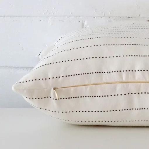 Enlarged image of the side of this linen cushion. The angle highlights how the rectangle design and striped decorative finish are joined along the seam.