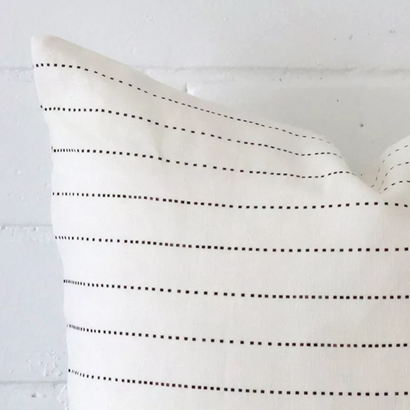 A zoomed in photo of the corner of a striped cushion that has linen fabric and a square size.