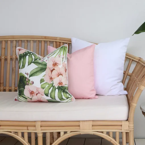 A set of three pink coloured outdoor cushions arranged beautifully on a rattan seat.