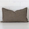 A rectangle gingham cushion in a delightful tone rests against a white wall. The designer material appears to be of exceptional quality.
