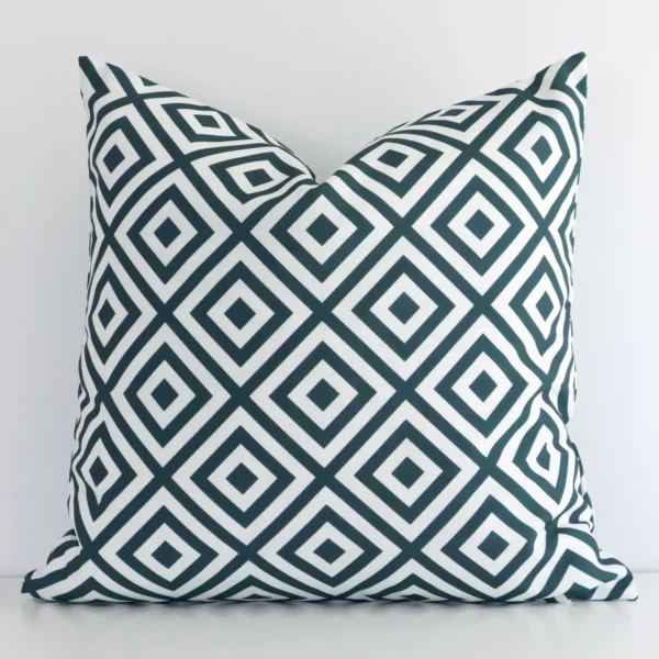 Green geometric cushion leans elegantly against a white wall. It has been crafted from a high quality outdoor material and has a square shape.