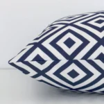 Outdoor navy geometric printed cushion laying on its side. The design and its square size are visible.
