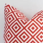 Zoomed in visual of an outdoor square cushion cover in red print. The intricacies of its geometric design are visible.