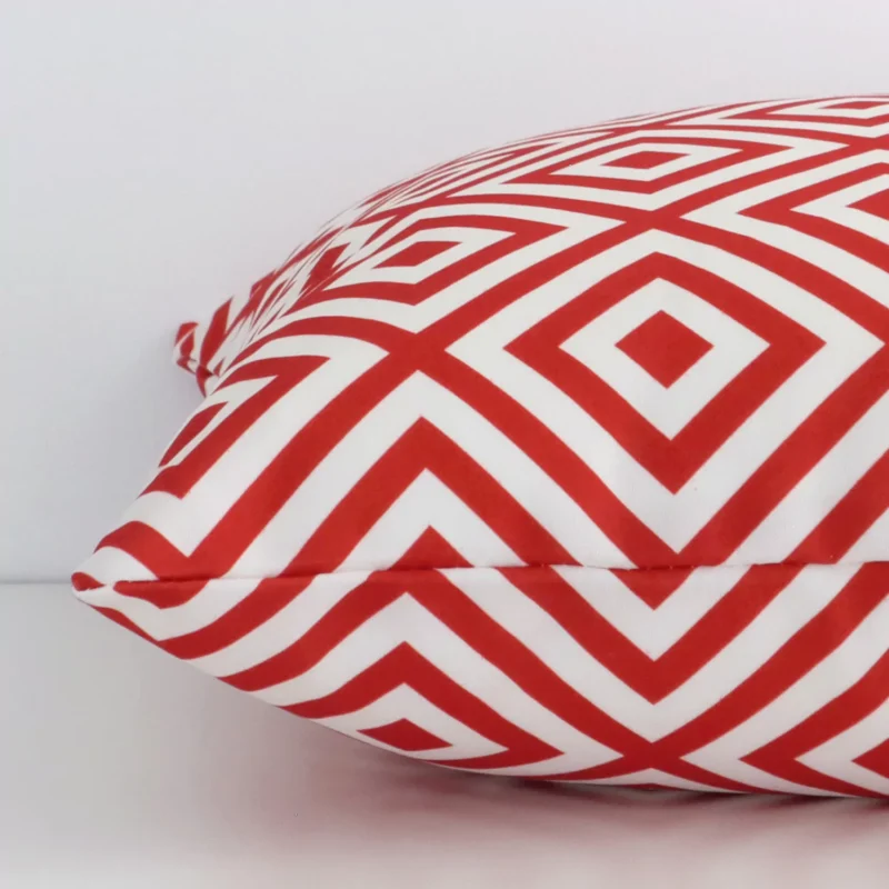 A sideways perspective of this geometric outdoor cushion. The positioning shows the border of the d shasquare and the red print colour.