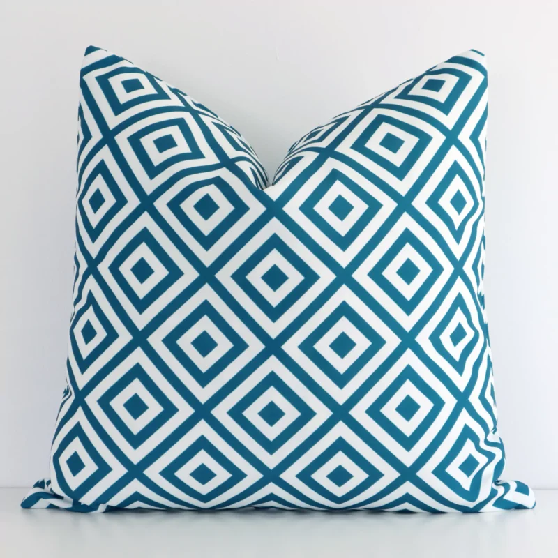 otama-geometric-waterproof-teal-outdoor-cushion-cover---sc723-45 Teal outdoor cushion cover features prominently against a white wall. It is a square design and has a geometric decorative finish.