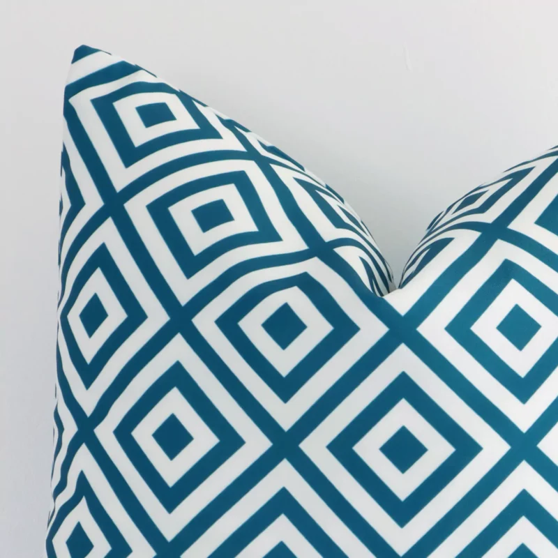 A detailed shot of this teal geometric cushion cover that has outdoor fabric and has a square size.