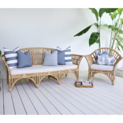 7 grey cushions with various designs arranged on rattan seats next to a green plant.