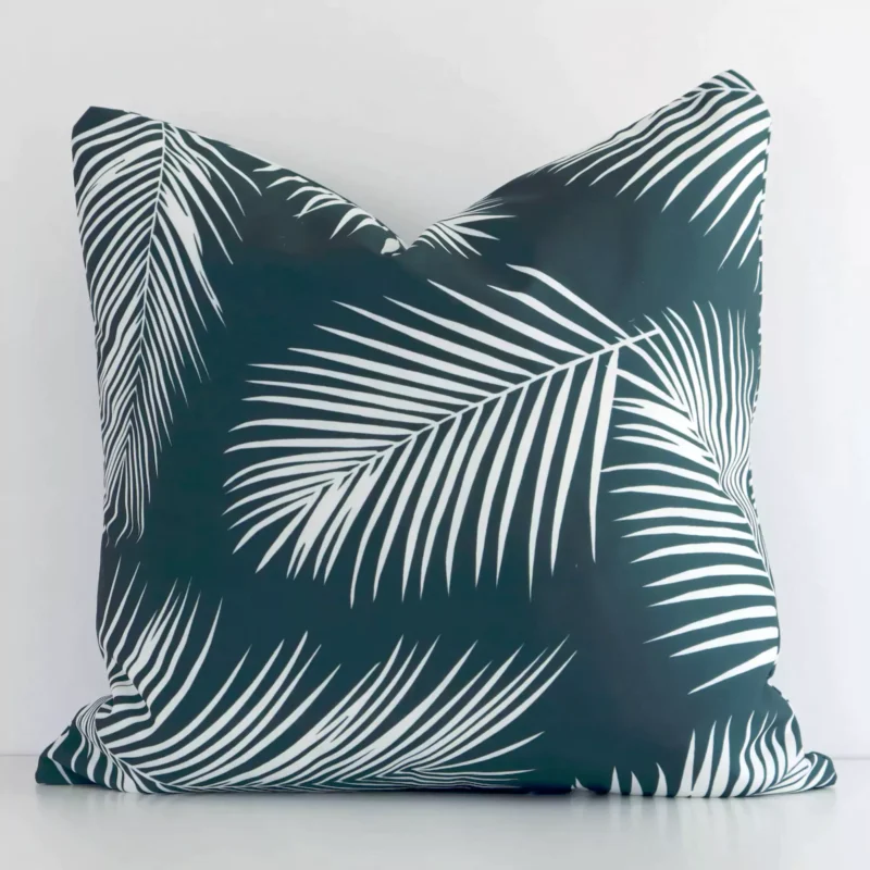 otama-palm-waterproof-green-outdoor-cushion-cover-SC950-45 A square palm styled cushion in a delightful green tone rests against a white wall. The outdoor material appears to be of exceptional quality.