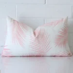 A rectangle cushion in a delightful pink tone rests against a white wall. The outdoor material appears to be of exceptional quality.