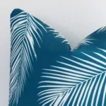 Enlarged shot of a square teal cushion cover that highlights that palm motif on its outdoor fabric.
