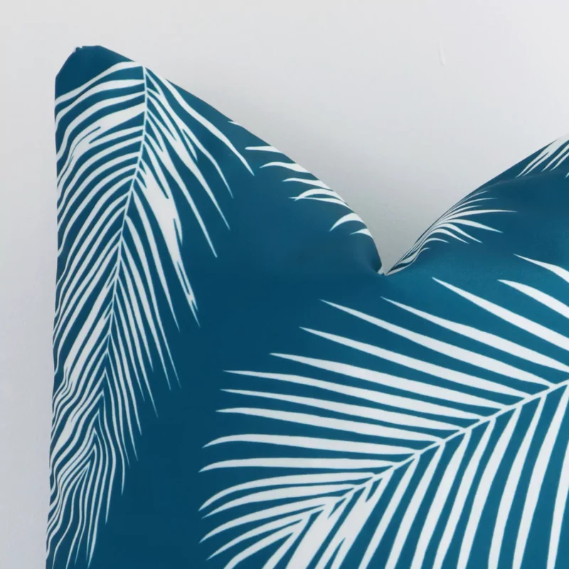 Enlarged shot of a square teal cushion cover that highlights that palm motif on its outdoor fabric.