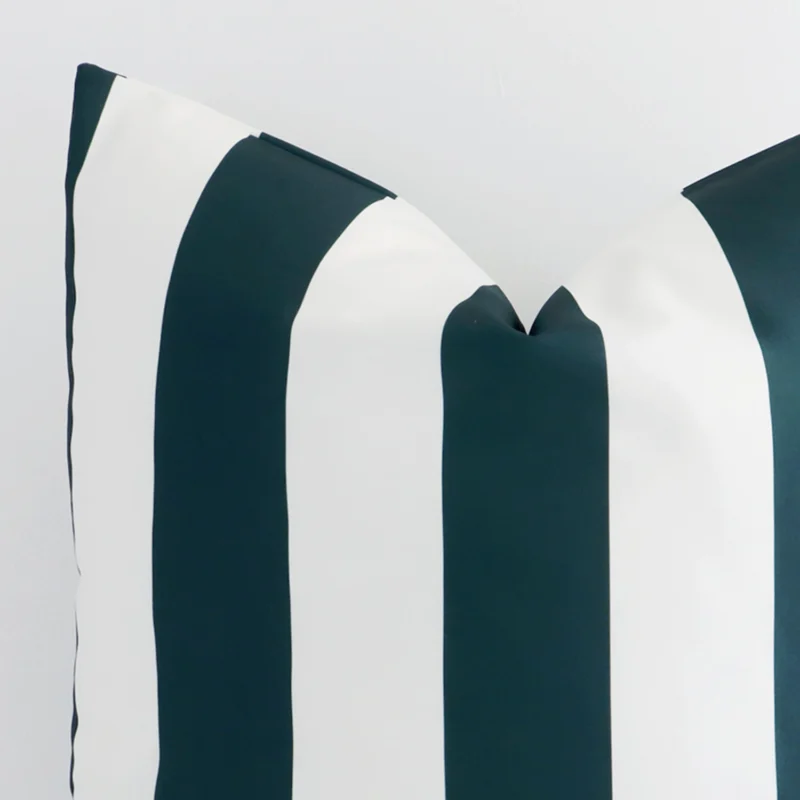 The corner of this green outdoor cushion is shown close up. The finer detail of its large design and striped decorative finish can be seen.