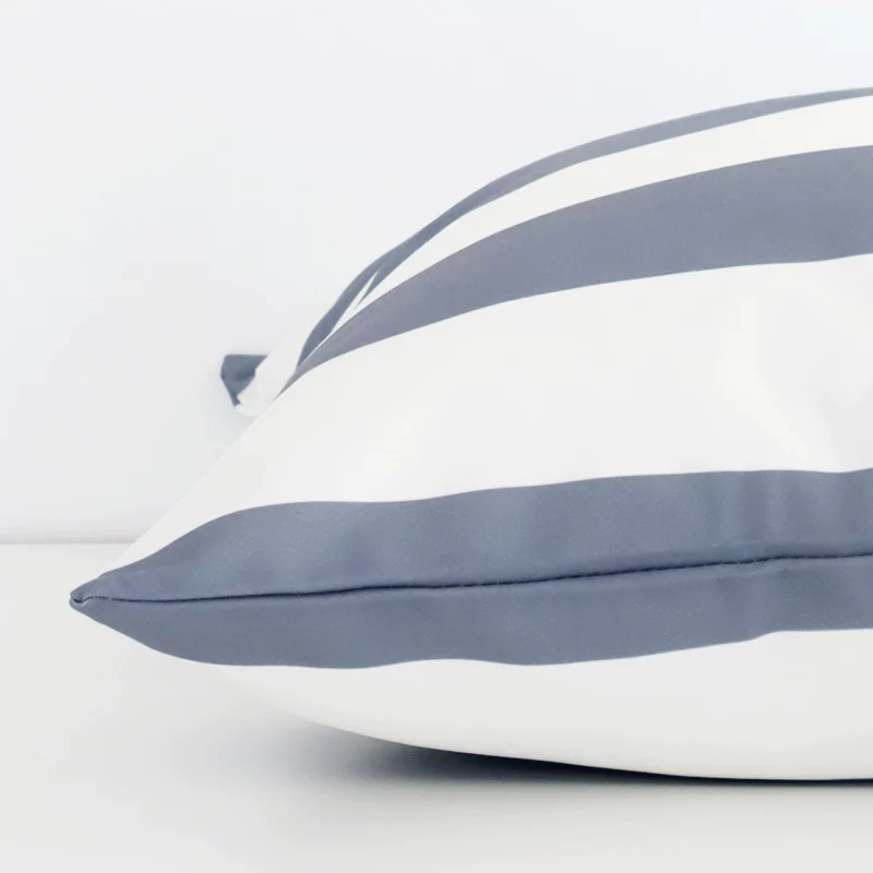 Grey stripe cushion cover laying sideways against white wall. The large size and outdoor material are shown highlighting the seams.