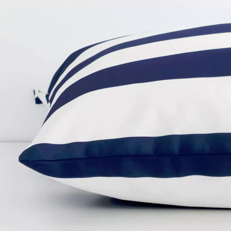 Striped navy cushion laid horizontally. This perspective shows the edge of the outdoor fabric and its large shape.
