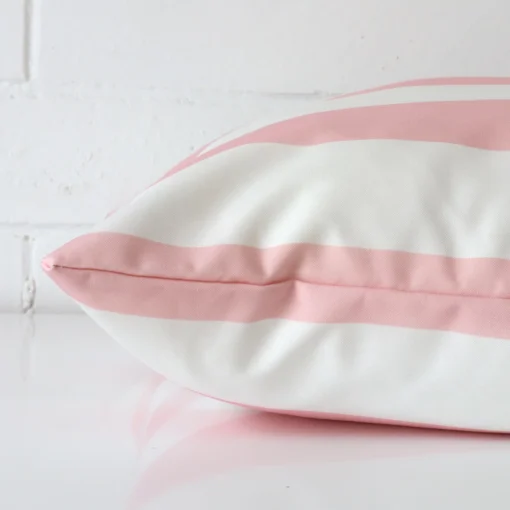 A pink cushion cover laying flat. This viewpoint highlights the outdoor fabric from a side position.