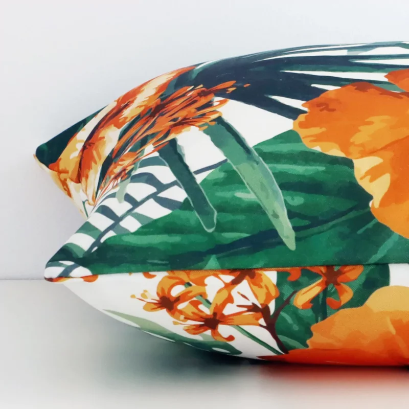 Linen orange cushion laying on its side. The floral design and its square size are visible.
