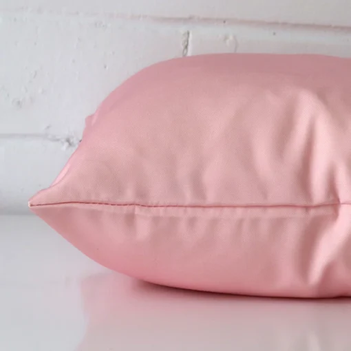 The seams of this outdoor square cushion cover in pink are shown.