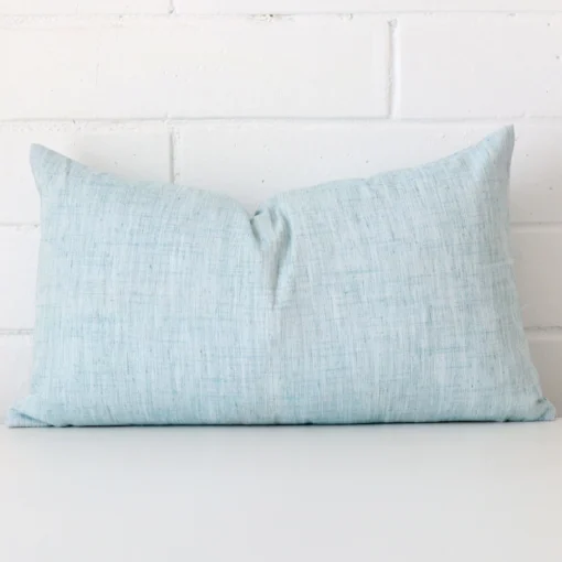 A pretty linen cushion cover is shown against a brick wall. It features a rectangle shape and a duck egg colour finish.