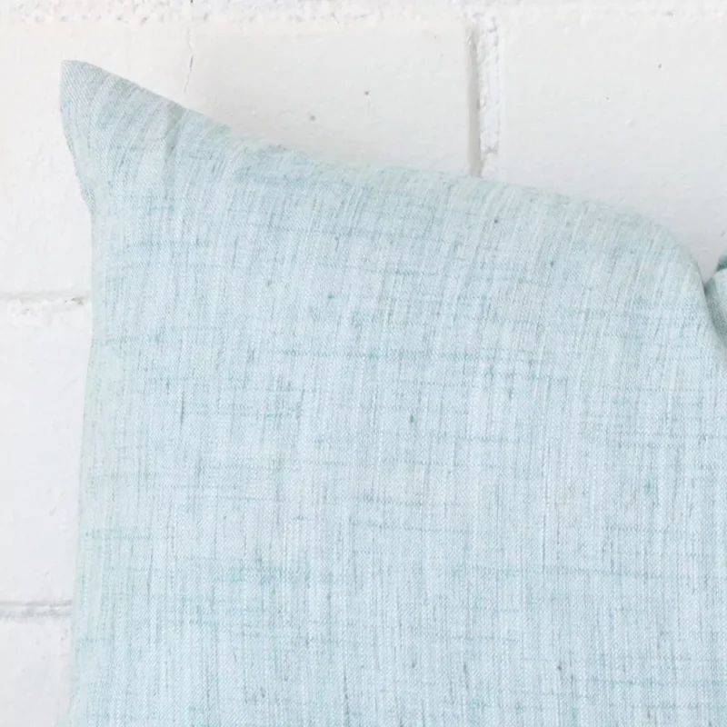 Horizontal edge view of front and back panels of a linen cushion in a rectangle size and with duck egg colouring.