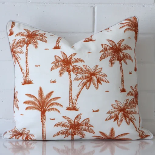 A lovely square terracotta cushion cover arranged in front of a white wall. The style complements the outdoor material.