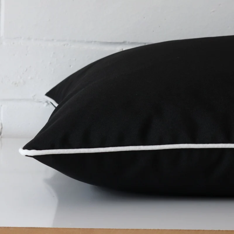 Large cushion in black colour laying flat. The viewpoint highlights the seams of the outdoor fabric.