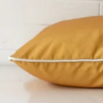 A side shot of an outdoor cushion cover. The angle shows the edge and the mustard tone with more clarity.