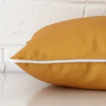 A rectangle outdoor cushion positioned flat to show its seams. The mustard colour is shown up close.