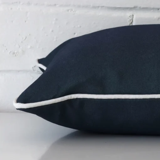 An outdoor navy blue cushion cover shown laying on its side. It has a rectangle shape.