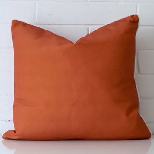 A pretty linen cushion cover is shown against a brick wall. It features a large size and a terracotta colour finish.