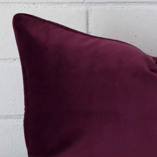 A very close image of the corner of a velvet cushion.The finer detail of the rectangle shape and purple colour are visible.