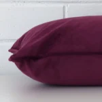 A velvet plum cushion cover shown laying on its side. It has a rectangle design.