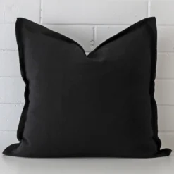 A hero shot of a large cushion cover. It is made from a deluxe linen fabric and features a black colour.