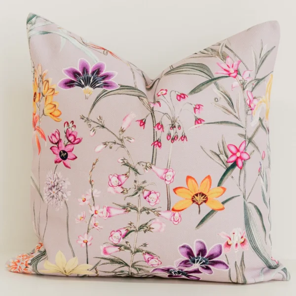 Multicolour wildflower print cushion cover on dusty mauve fabric.