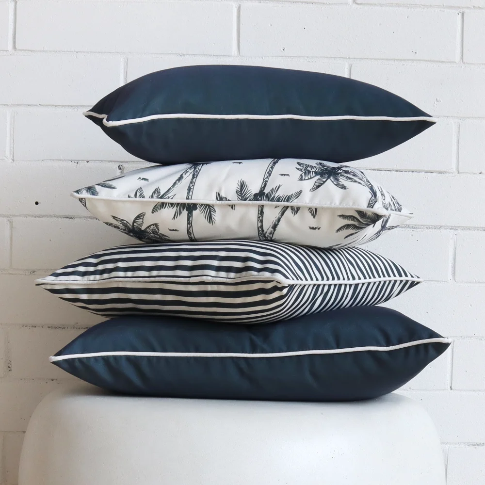 A round side table is shown with a stack of navy outdoor cushions on it.