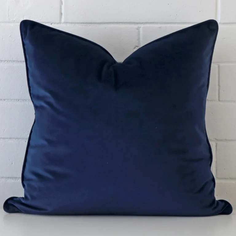 A lovely large blue cushion cover arranged in front of a white wall. It is made from a soft velvet material.