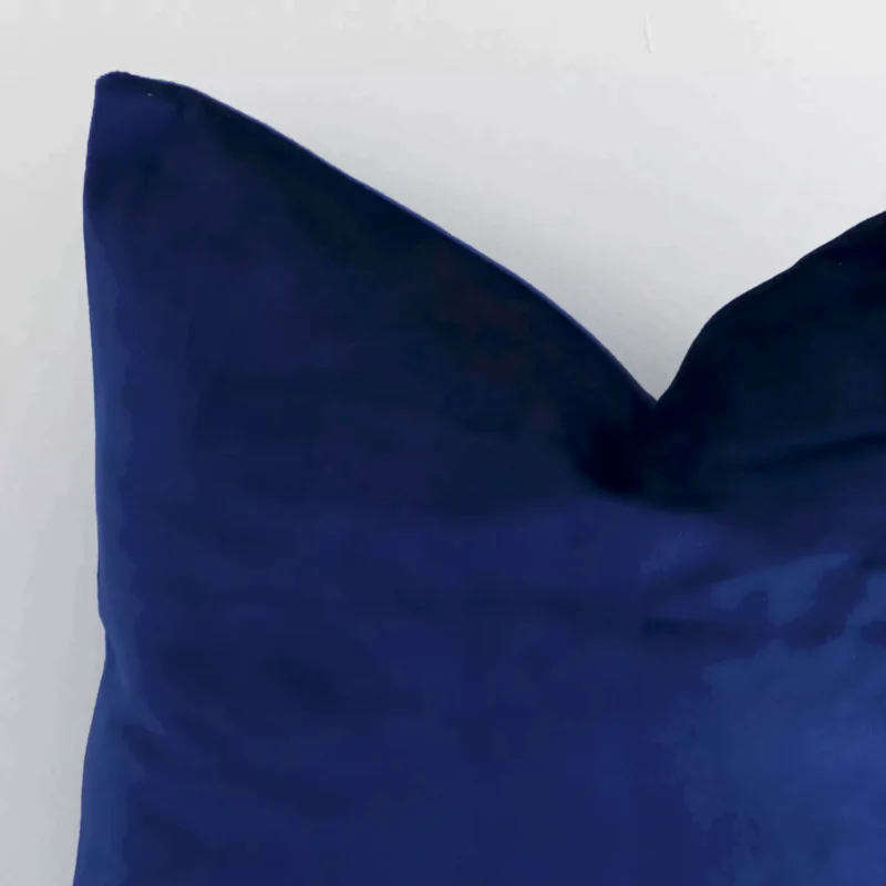 Corner section image showing features of square royal blue cushion that has a solid colour motif on its velvet fabric.