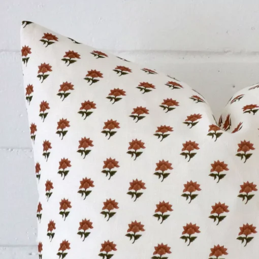 Enlarged shot of a square terracotta cushion cover that highlights that floral motif on its linen fabric.