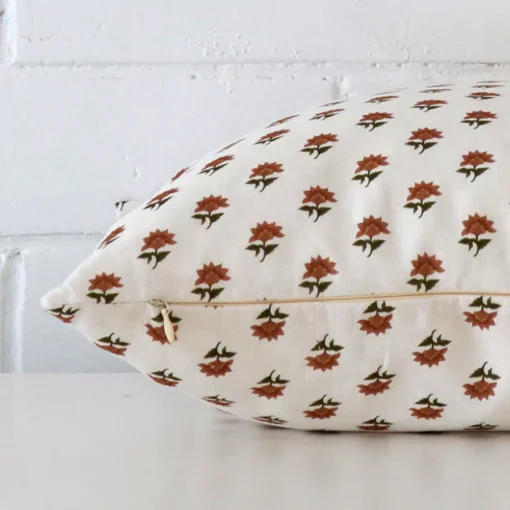 Horizontal edge of floral square cushion cover is shown. The linen fabric and terracotta tone can be seen from this side view.